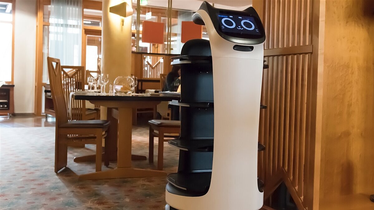 Ein Serviceroboter steht in einem Gastraum. 