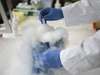 Ein Mann tröpfelt im Labor mit einer Pipette in einen rauchenden Behälter.