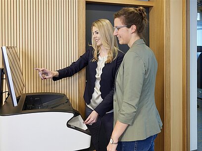 Zwei junge Frauen bedienen einen Drucker.