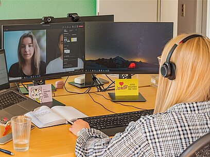 Eine junge Frau sitzt vor dem Computer während einer virtuellen Besprechung.