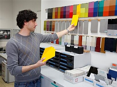 Ein junger Mann ordnet Farbkarten dem richtigen Farbton zu.
