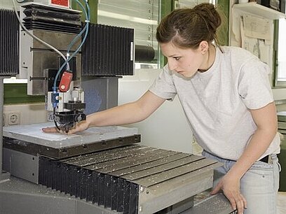 Eine junge Frau bedient eine Sägemaschine für Metallteile.