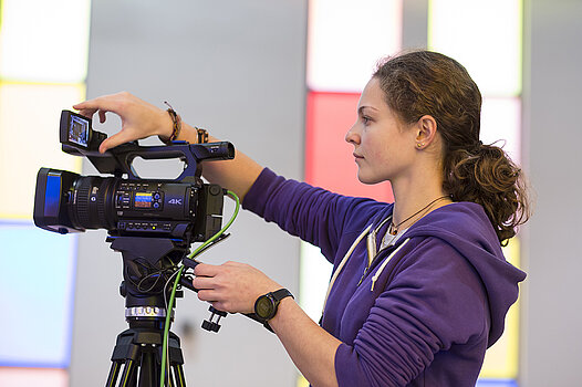 Eine junge Frau nimmt Einstellungen an einer Kamera vor.