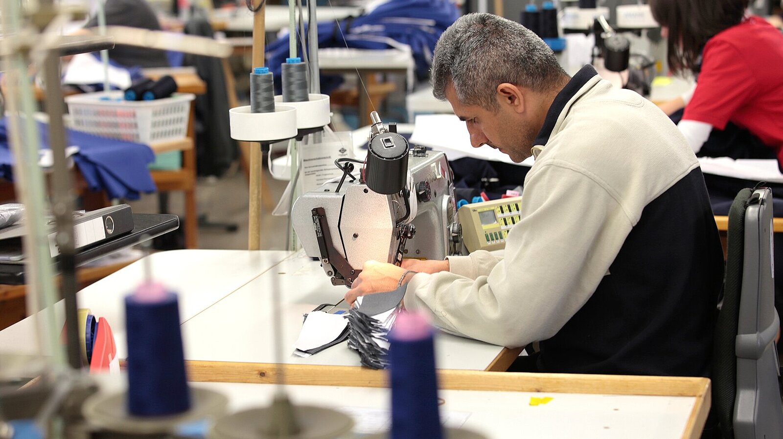 Ein Mann richtet eine Nähmaschine für die Serienfertigung ein.