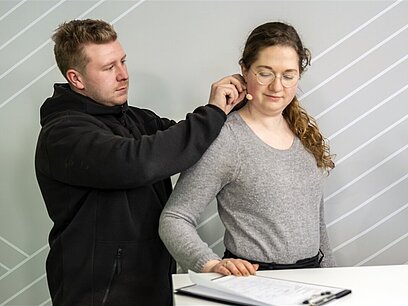 Ein Mann befestigt einer Frau das Mikrofon an der Wange.