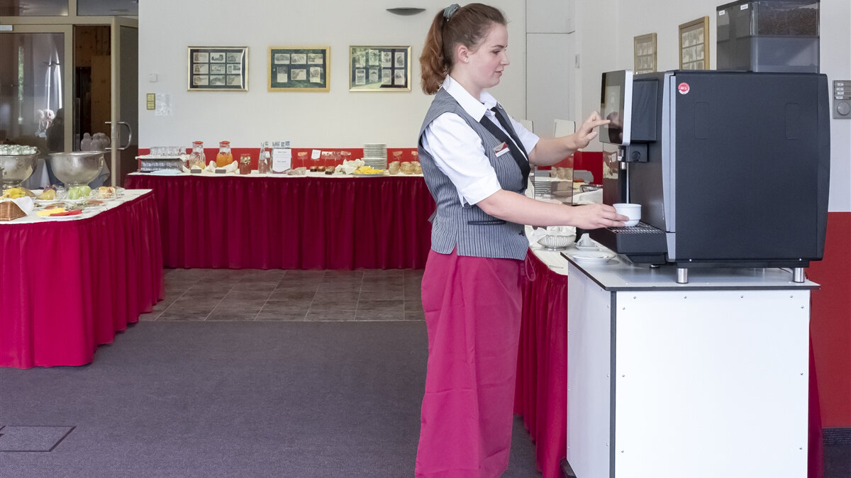 Nicole bedient den Kaffeeautomaten im Frühstücksraum des Hotels.