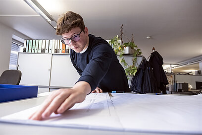 Ein junger Mann nimmt auf einem Stück Papier Maß.