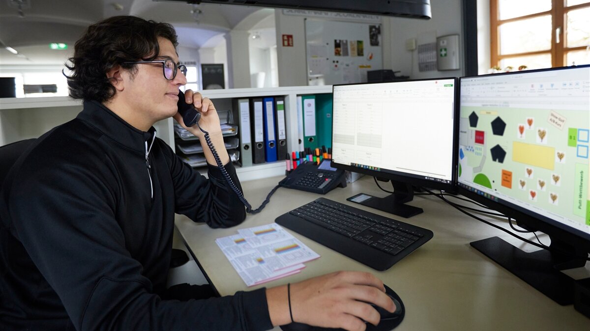 Ben-Luca ist am Telefon vor seinem Computer mit dem Lageplan des Golfclubs. 