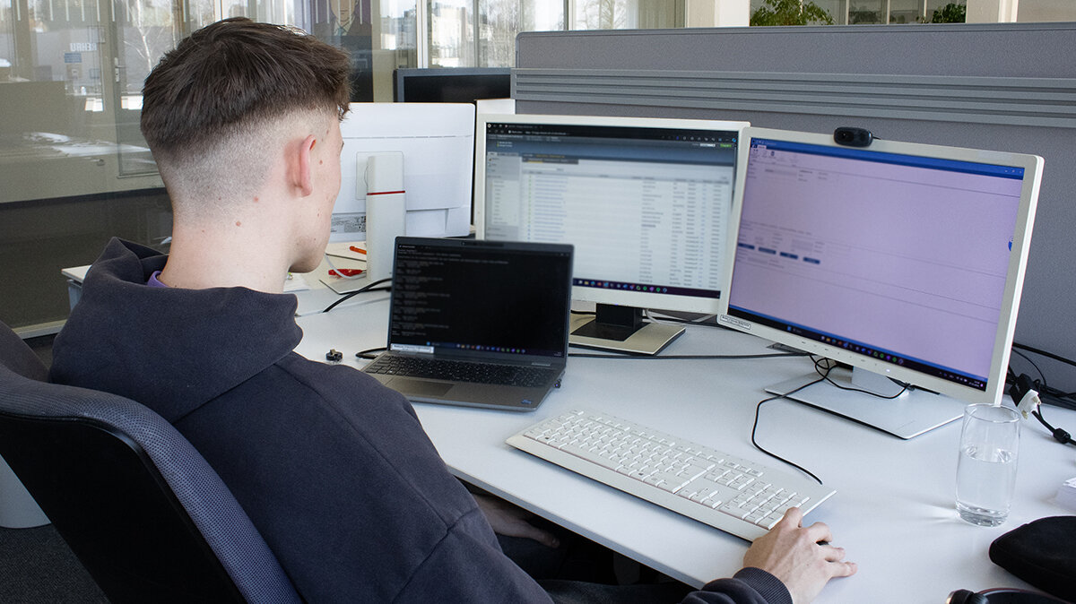 Paul sitzt an seinem Schreibtisch vor mehreren Bildschirmen und nimmt virtuelle Server in ein Portal auf.