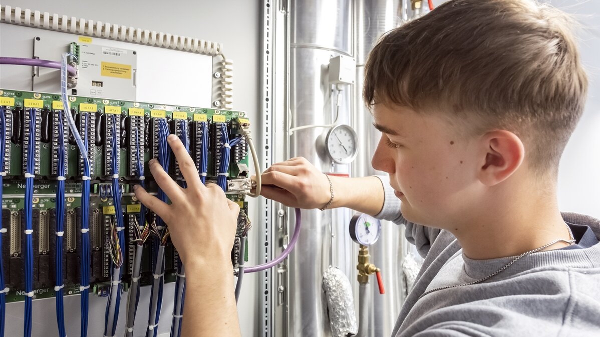 Fabian setzt das neue Kabel in den Schaltschrank ein.