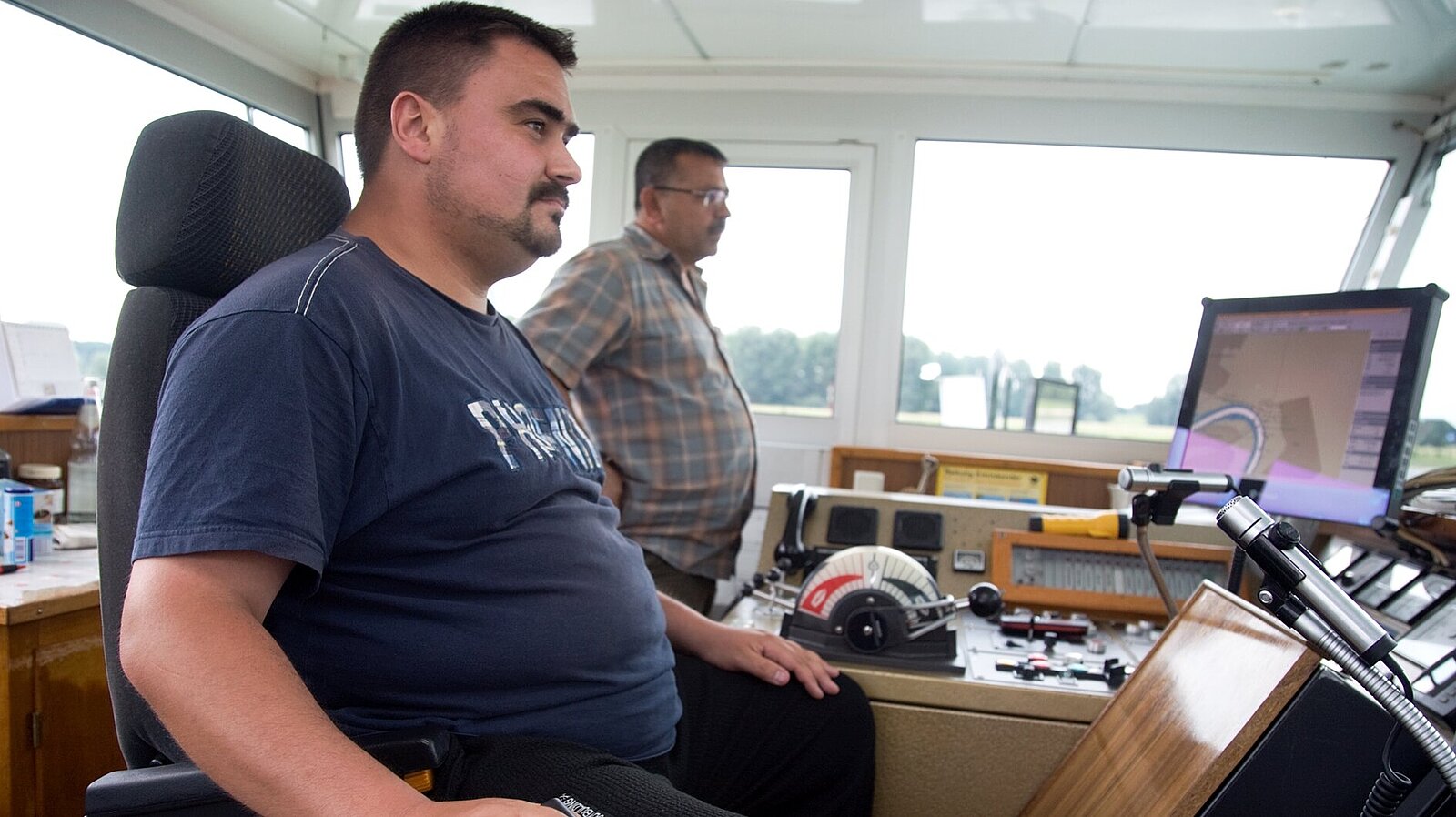 Ein Mann steuert ein Schiff von der Brücke aus.