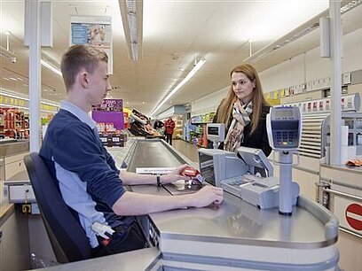 Eine junge Frau bezahlt an einer Supermarktkasse.