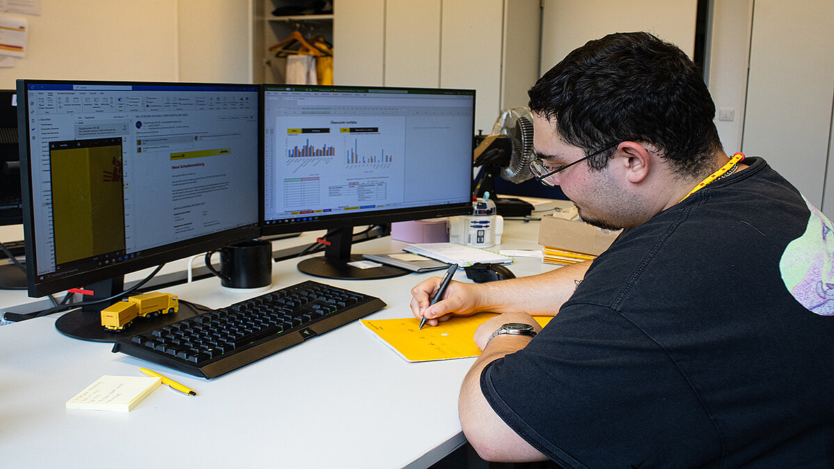 Michael sitzt im Büro und beschriftet eine Umlaufmappe.