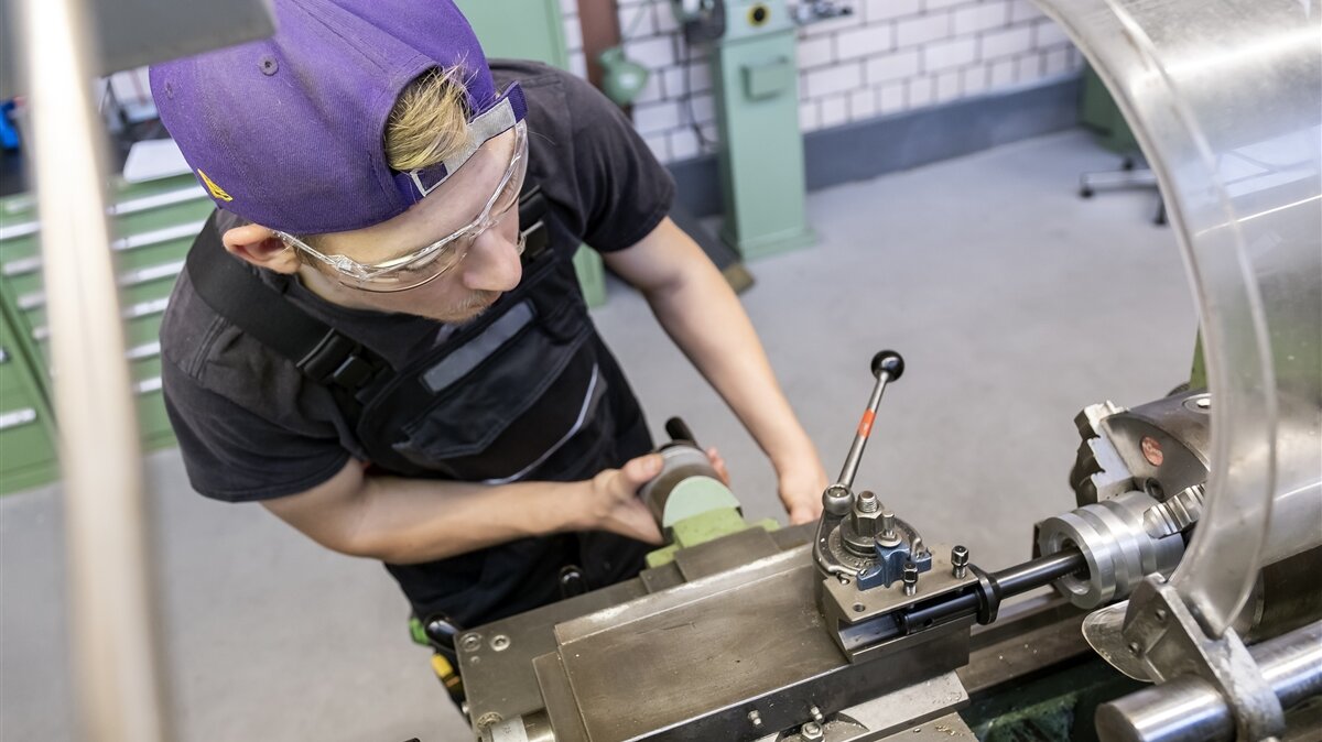 Luca arbeitet mit dem Ausdrehwerkzeug an der Drehmaschine und trägt dabei eine Schutzbrille