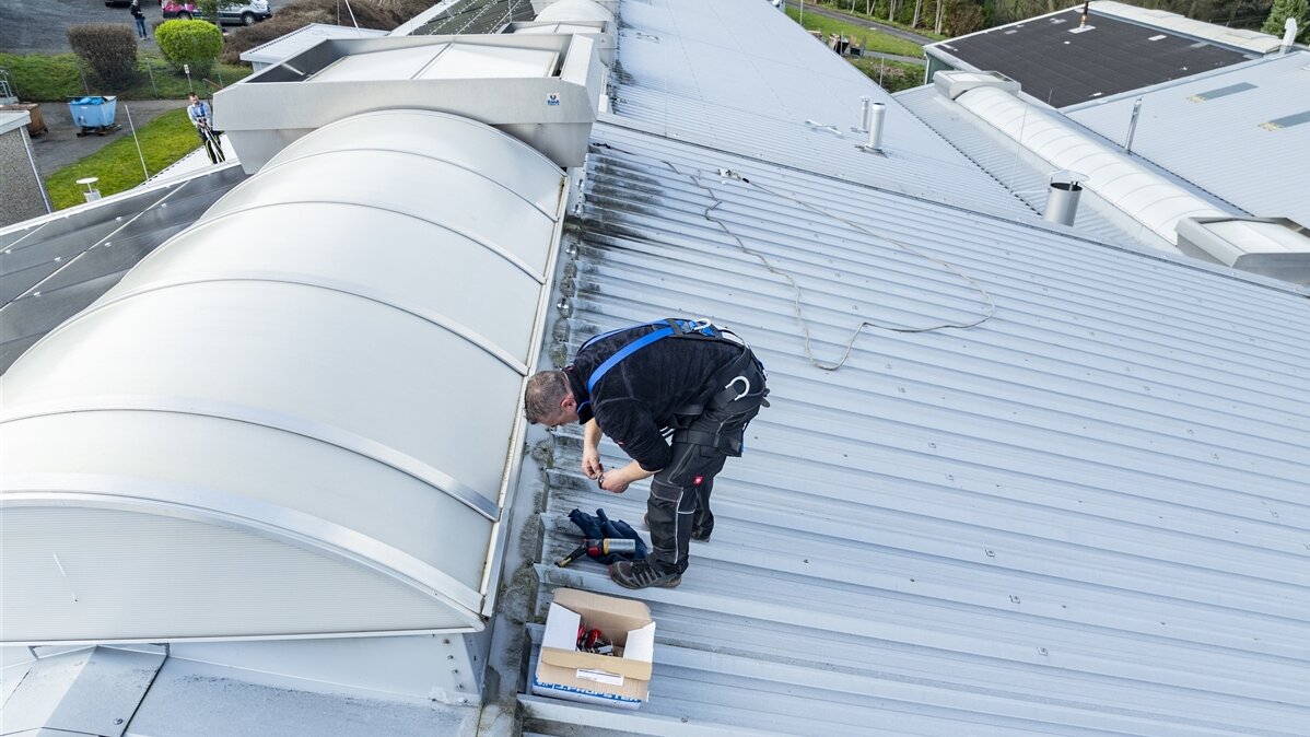 Ein junger Mann packt seine Arbeitsgegenstände auf dem Dach aus.