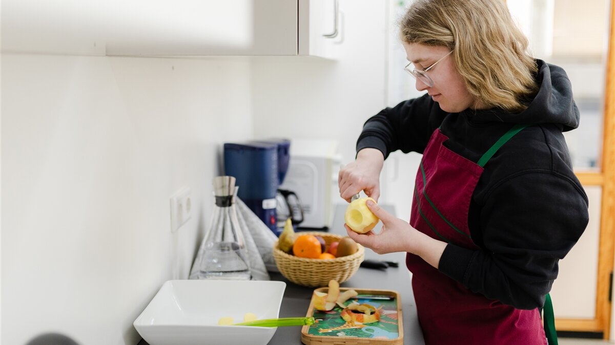 Leonie-Marie schält einen Apfel über der Arbeitsplatte einer Küche.