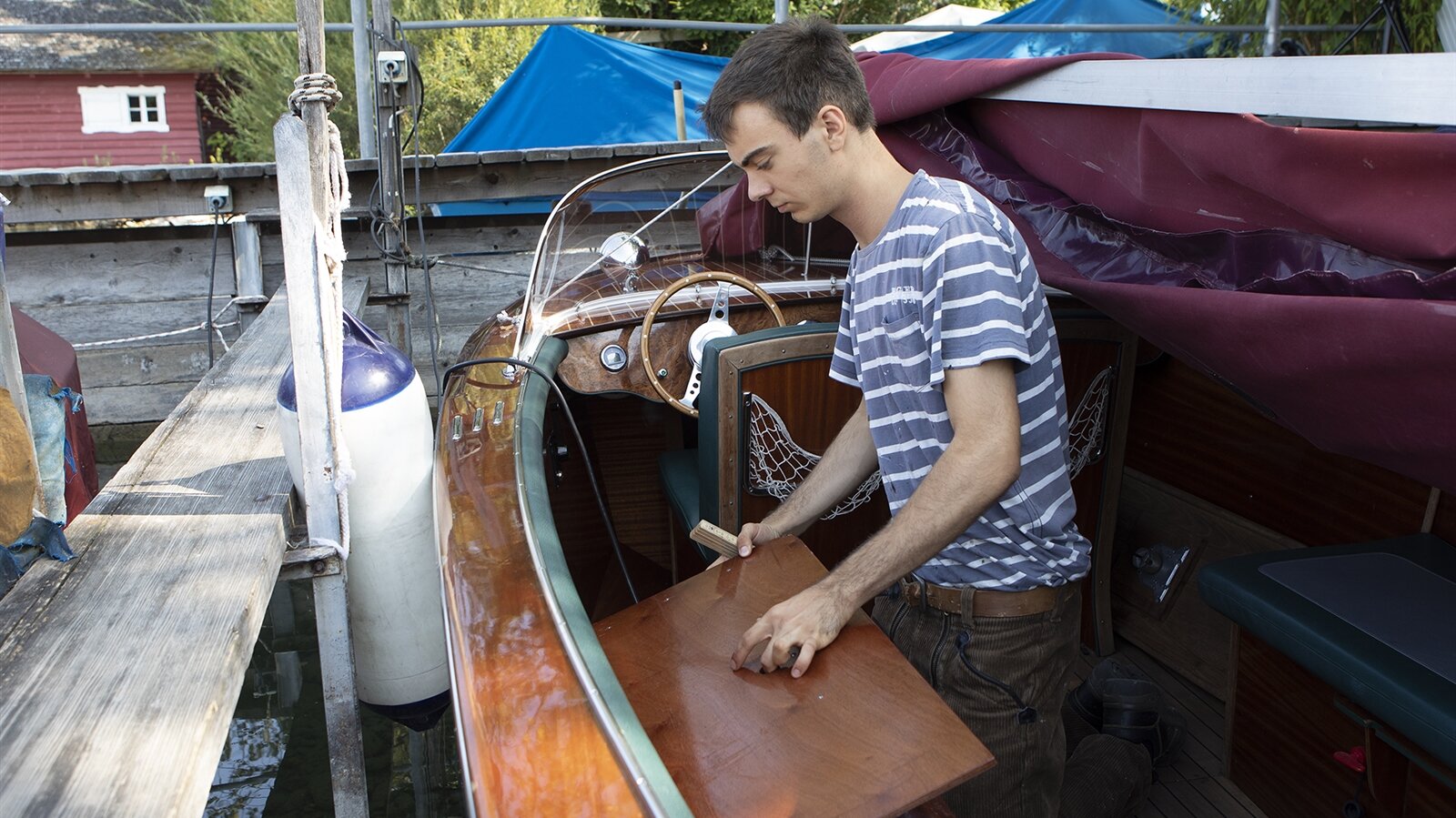 Benedikt tauscht den alten Deckel mit dem neuen aus, das E-Boot liegt im Wasser im Hafen.