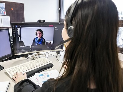 Eine junge Frau hat eine Onlinebesprechung über den Computer.