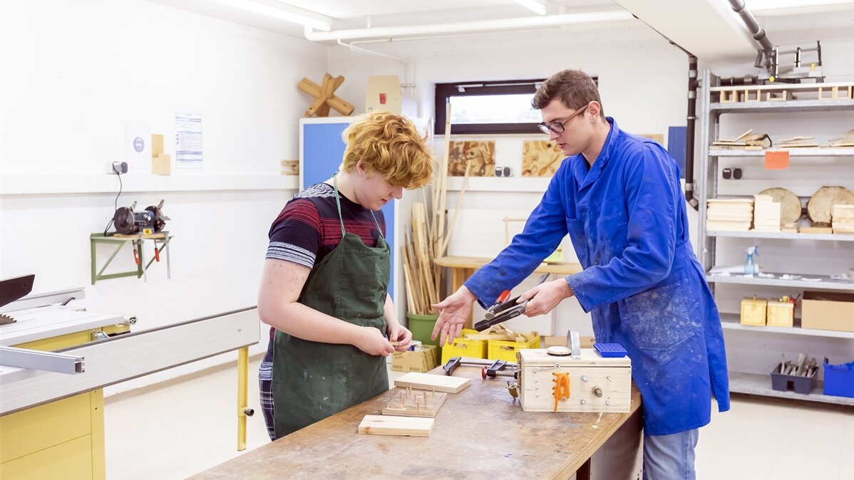 Zwei junge Männer arbeiten mit Holz.