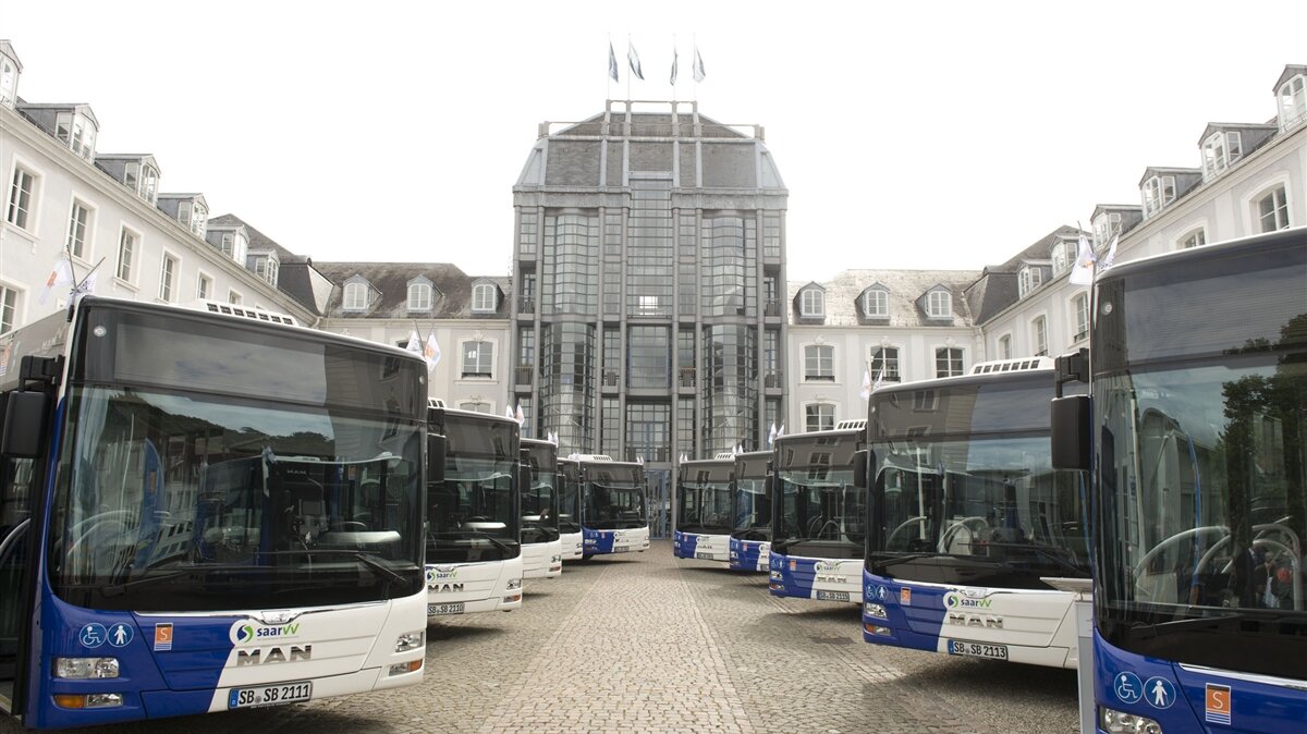 Busse stehen geordnet auf einem Platz.
