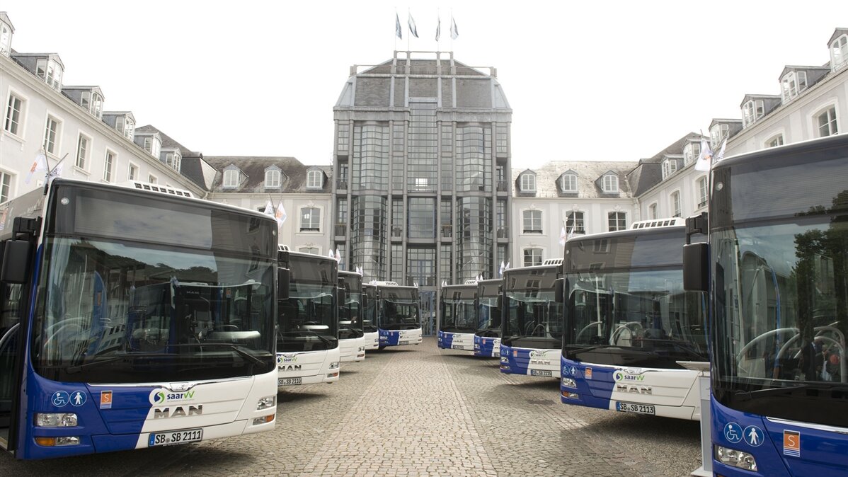Busse stehen geordnet auf einem Platz.