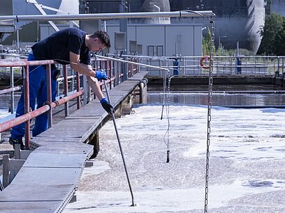 Ein junger Mann entnimmt eine Abwasserprobe.