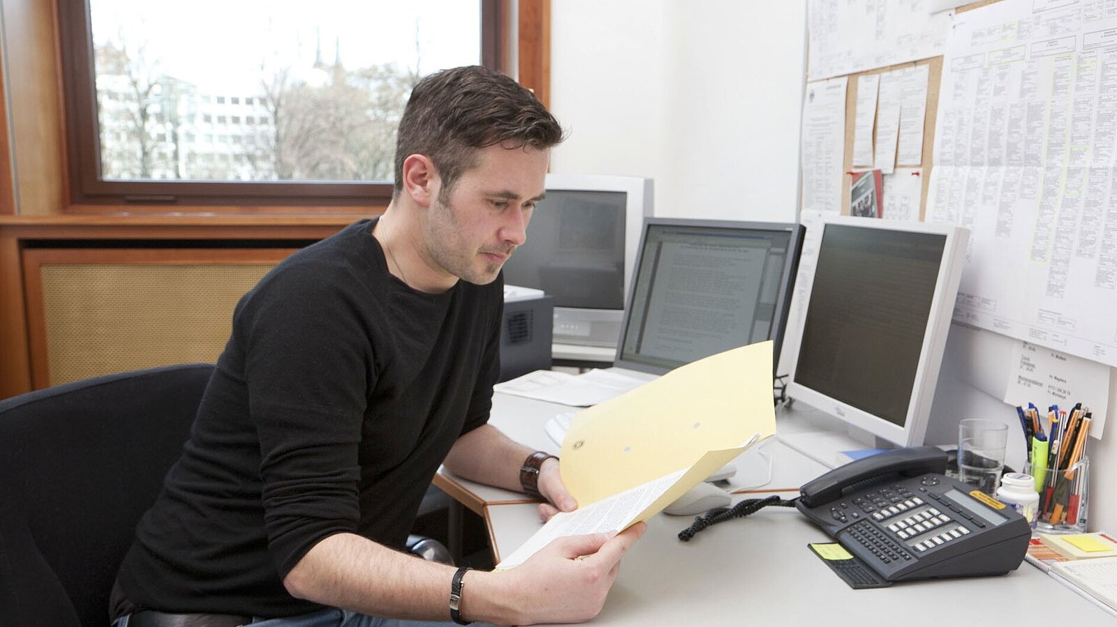 Ein Mann liest sich an seinem Schreibtisch Unterlagen durch