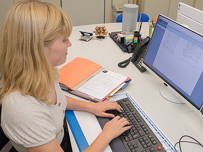Eine junge Frau arbeitet an einem Laptop.