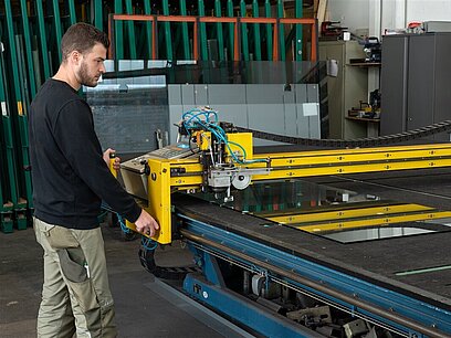 Ein junger Mann arbeitet in einer Produktionshalle an einer Maschine.