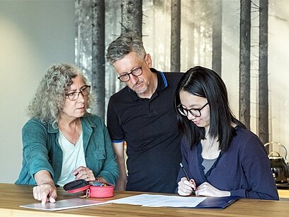 Eine junge Frau mit Bewerbungsunterlagen wird von ihren Eltern beraten.