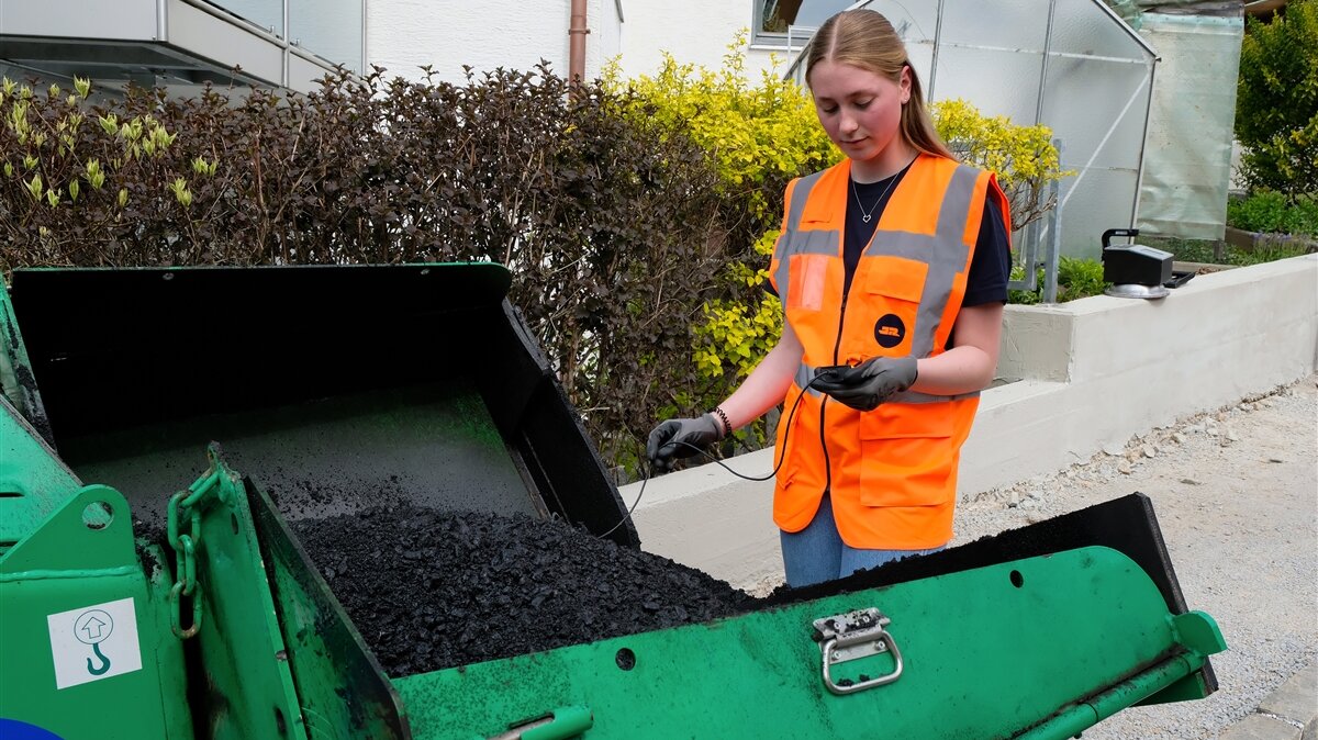 Anna misst die Temperatur von frischem Asphalt.