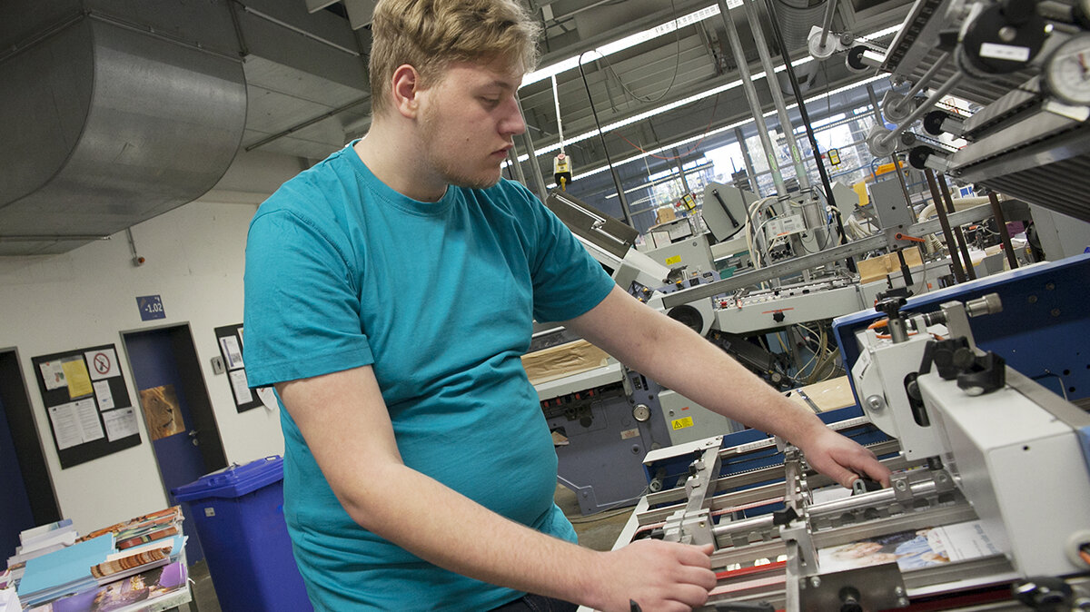 Ein junger Mann arbeitet an einer Druckverarbeitungsmaschine