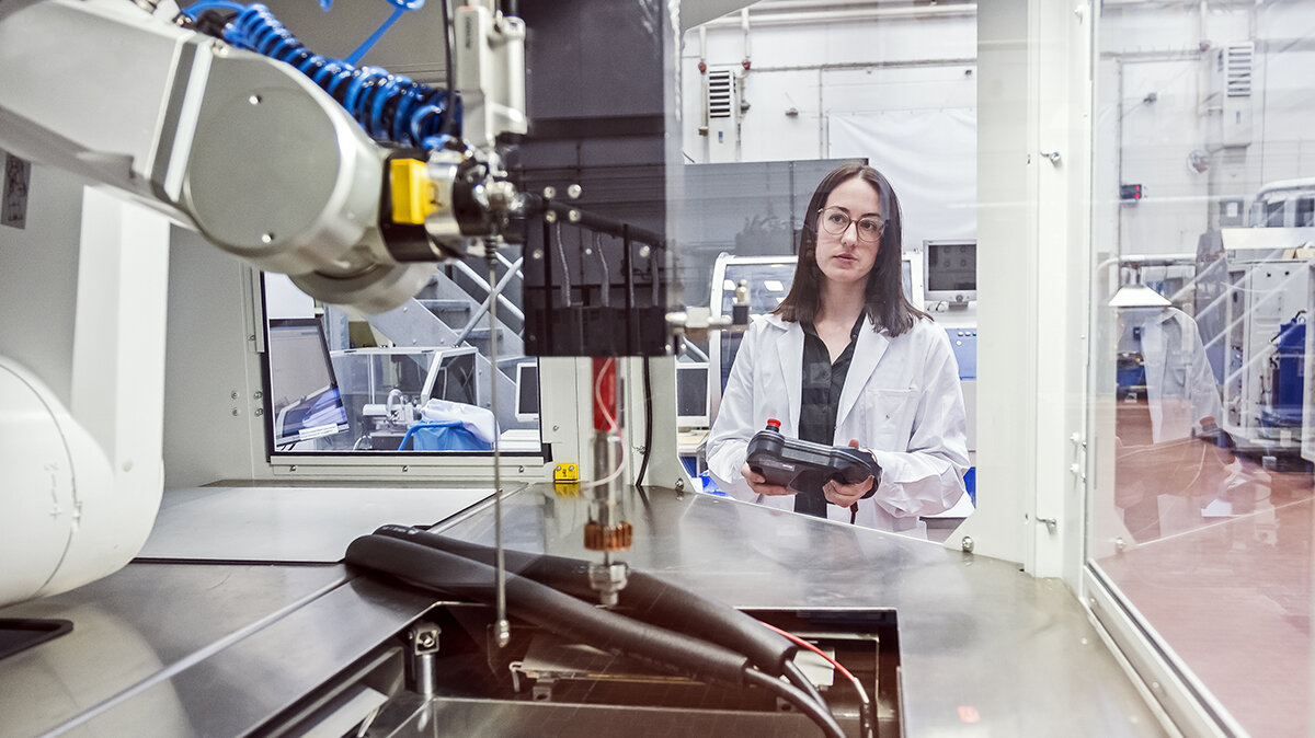 Eine junge Frau in Laborkleidung bedient eine Maschine.