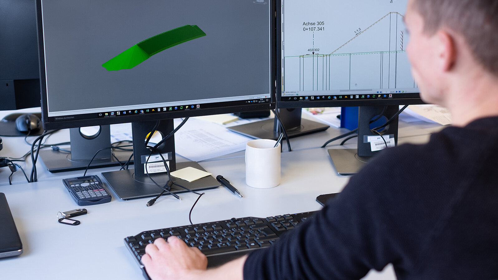 Willy sitzt am Schreibtisch vor zwei Monitoren und arbeitet mit der CAD-Software.