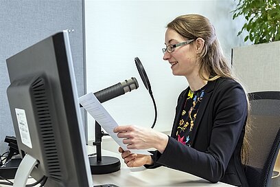 Eine Frau spricht in ein Aufnahme-Mikrofon.