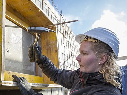 Eine Frau befestigt ein Schild an einer Baustelle.