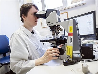 Ein Mann untersucht eine Probe mit einem Mikroskop.