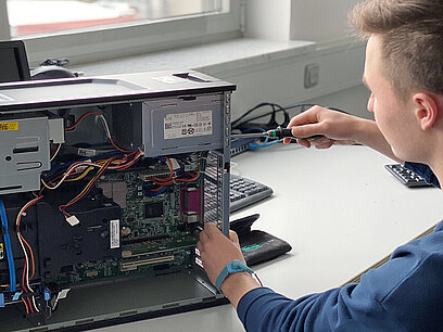 Ein junger Mann schraubt an einem Computerserver.