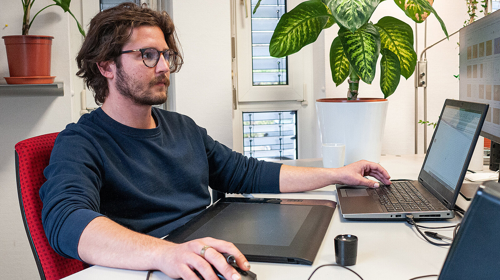 Ein Mann arbeitet am Schreibtisch mit einem Laptop.