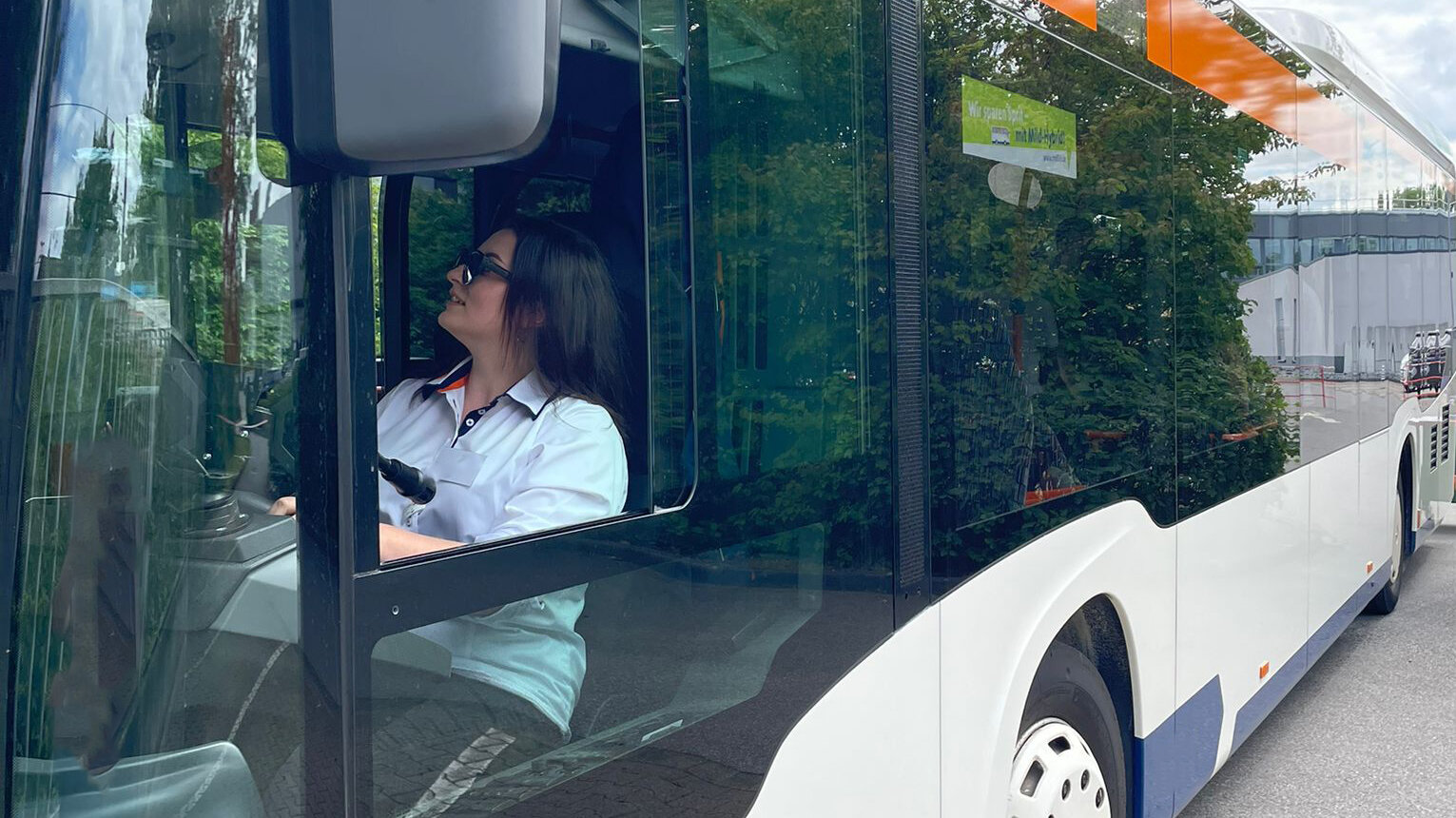 Ewa sitzt in der Fahrerkabine im Bus, schaut in den Rückspiegel und fährt rückwärts.