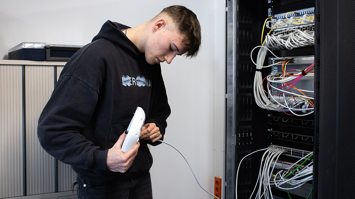 Paul schließt einen Access Point mit einem Kabel an einen Server an.