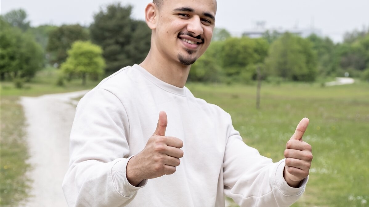Eine junger Mann reckt lachend beide Daumen.
