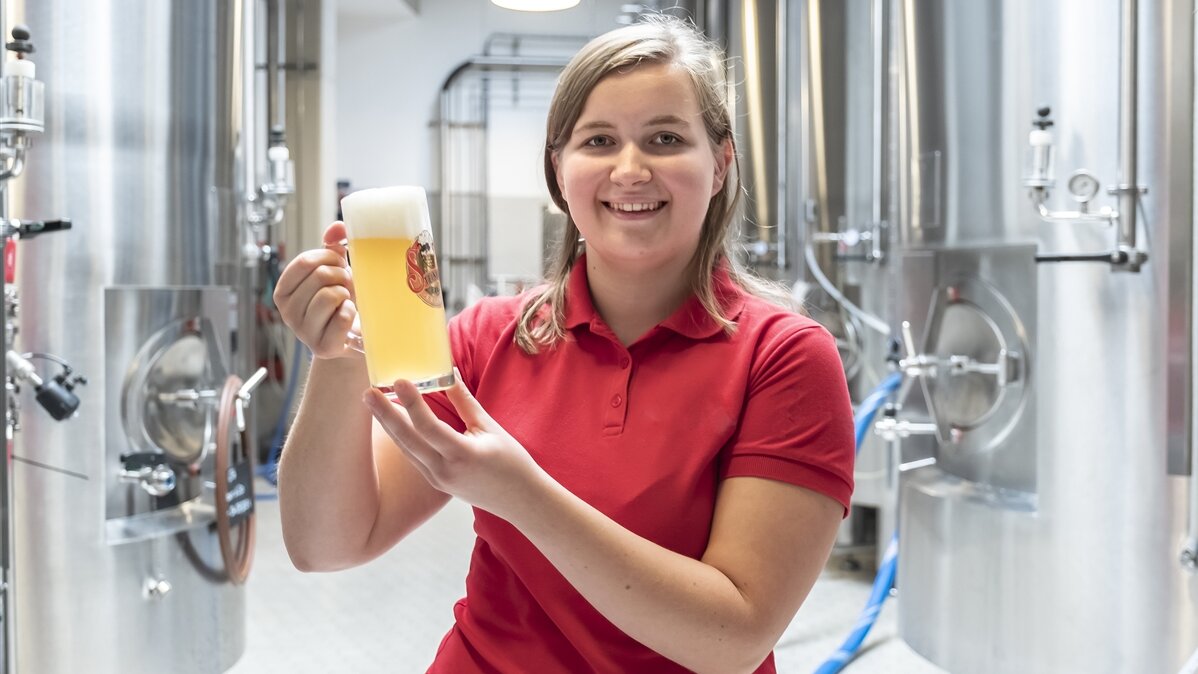 Porträtfoto von Luisa in der Brauerei. Sie hält ein Bierglas in der Hand. 
