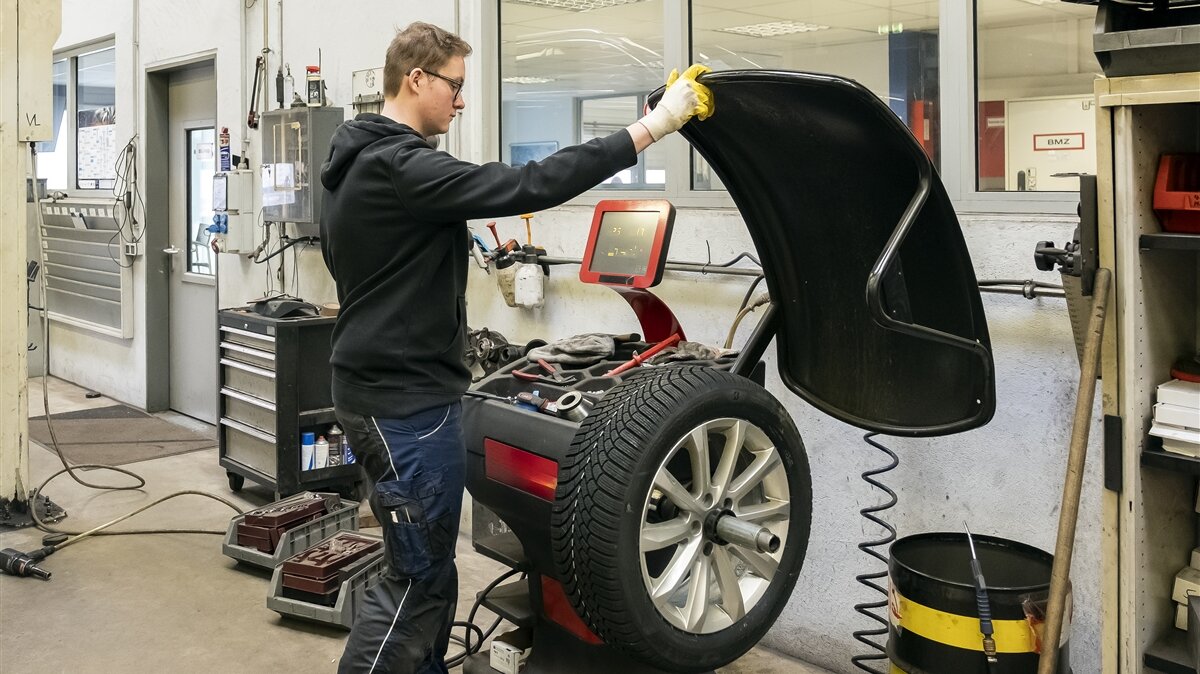 Tobias trägt Schutzhandschuhe und bedient die Auswuchtmaschine.