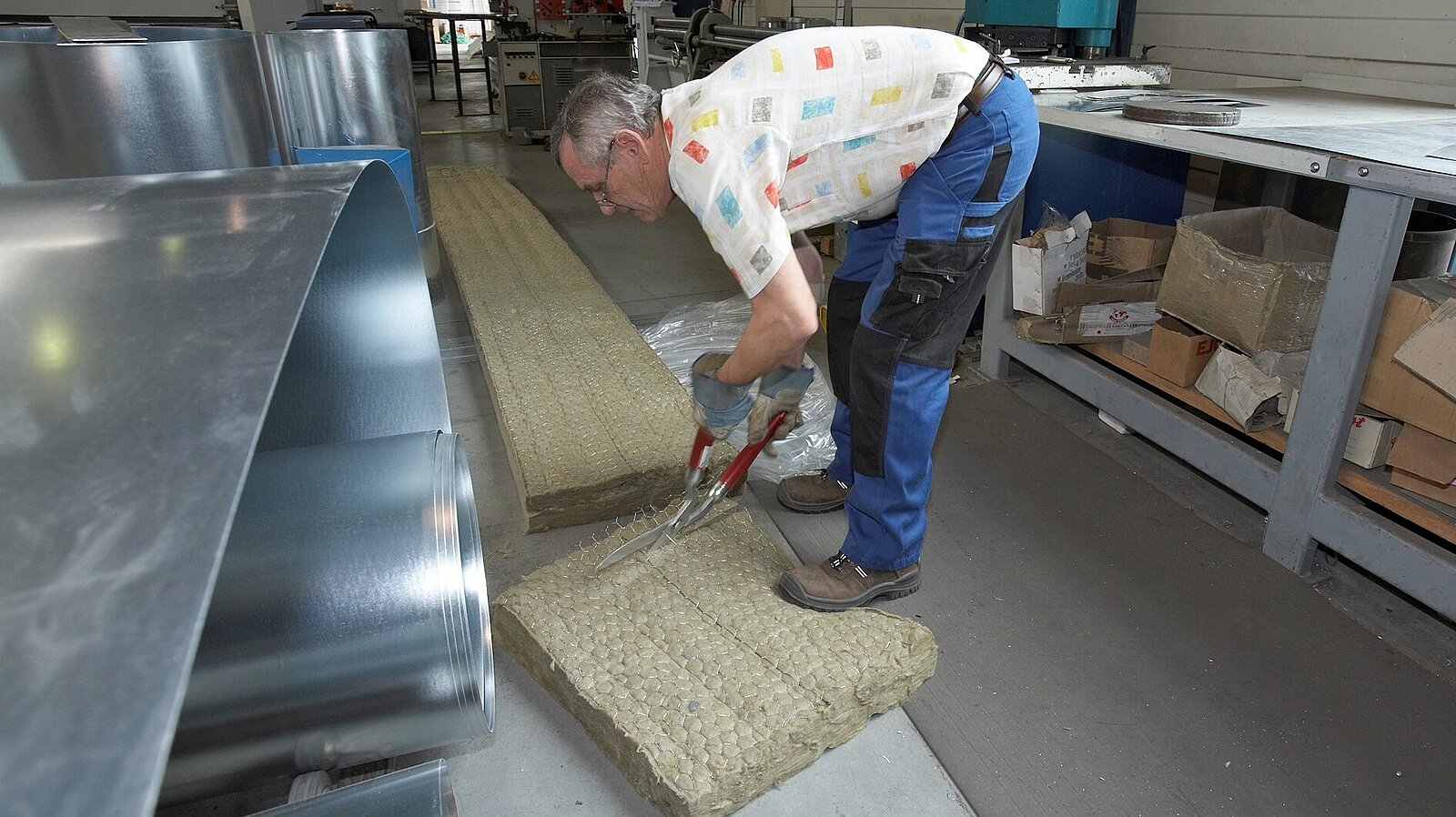 Ein Arbeiter schneidet Isolier-Material in Streifen.
