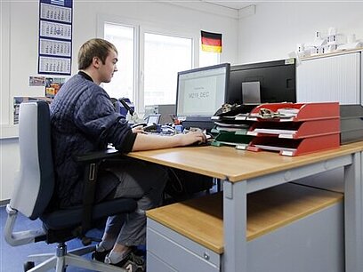 Ein junger Mann arbeitet im Büro an einem Computer.