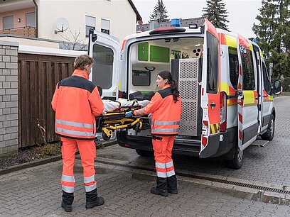 Zwei junge Notfallsanitäter bereiten einen Rettungswagen für den nächsten Einsatz vor