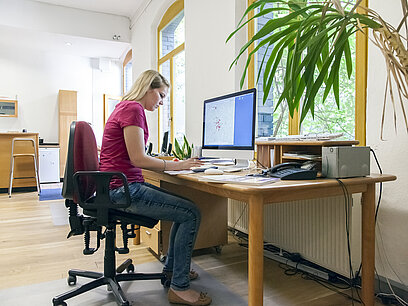 Eine Schülerin sitzt an ihrem Schreibtisch vor dem Bildschirm.