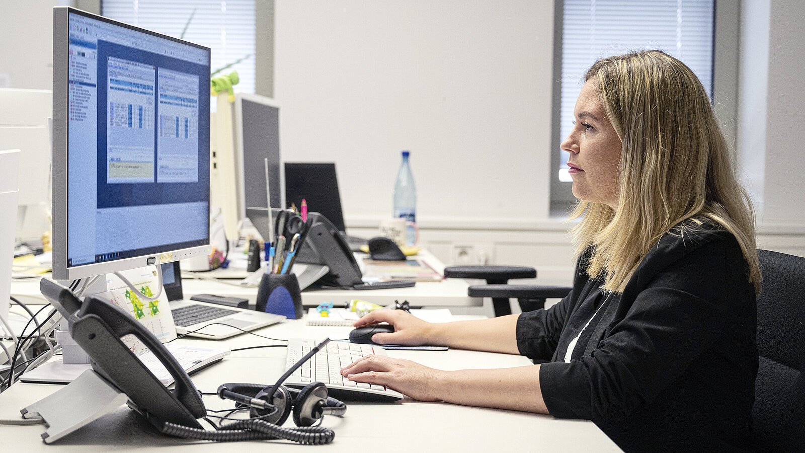 Eine junge Frau arbeitet im Büro am Computer.