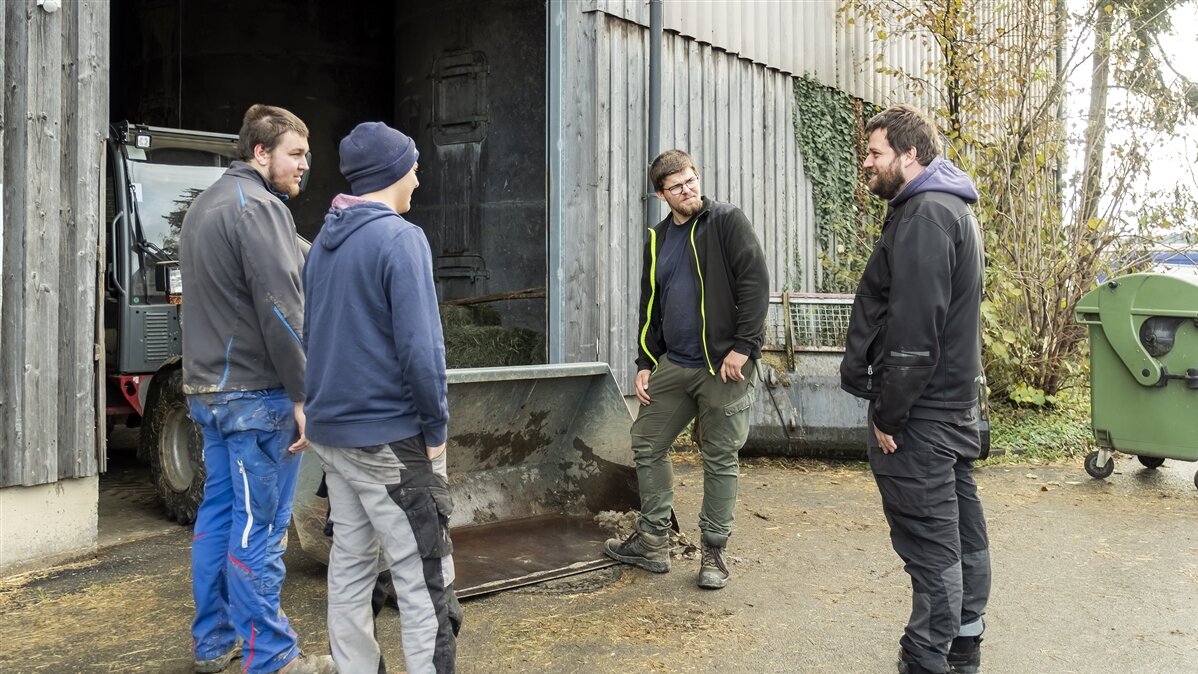 Jonathan und die beiden anderen Azubis bei der Besprechung mit dem Ausbilder vor dem Stall.